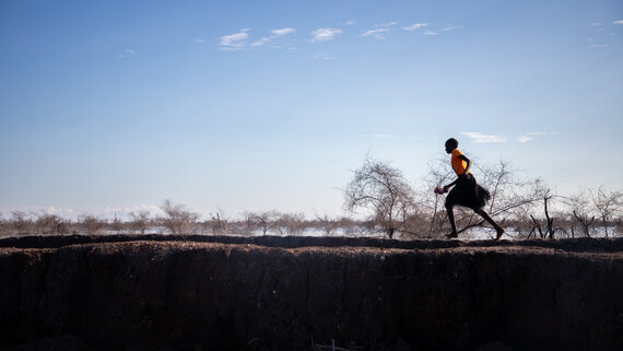 A young girl running past a dyke built to protect communities from the flooding.