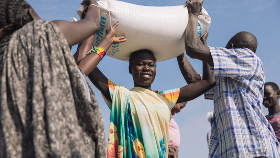 An IDP woman carries a sack of sorghum she received during general food distribution at Malakal PoC site in Upper Nile State.